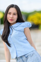 Young Woman in Blue Shirt with Long Hair in Outdoor Setting