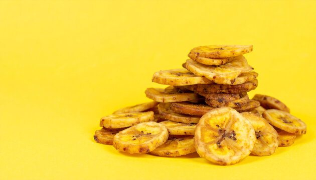 Banana Chips on Yellow: Sliced banana chips, crisped to golden perfection, arranged artfully against a backdrop of sunny yellow, offer a tempting glimpse into wholesome, guilt-free snacking.