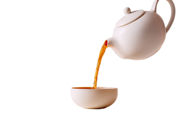 Hot tea pouring from a white teapot into a small white teacup