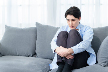 ソファでうずくまる男性