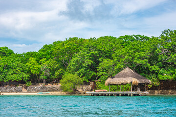 Beautiful landscape of Rosario Island, featuring lush greenery and a traditional thatched-roof...