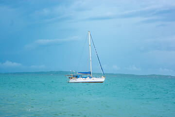 A serene sailboat floats on the turquoise waters of Rosario Island, near Cartagena, Colombia, with...