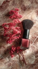 Pink nail polish and makeup brush beside dried flowers on marble