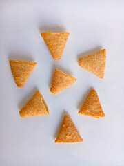 Top view of cone-shaped crispy snacks. Salty, textured corn chips arranged on a white background, an ideal concept for savory appetizers or junk food.
