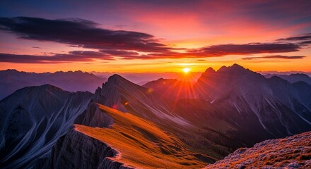 Majestic mountain range illuminated by a vibrant, fiery sunset with dramatic clouds painting the sky.
