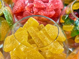 Colorful assortment of vibrant gummy candies filling transparent bowls at a lively market stall...