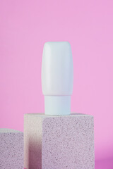 Plastic white tube for cream or lotion. Skin care or sunscreen cosmetic with stylish props on pink background.