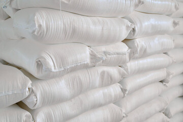 Storage facility filled with stacked bags of wheat flour at a bustling warehouse during peak...