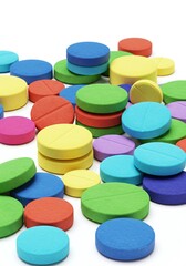 A vibrant and colorful collection of round pills and capsules scattered across a clean white background, symbolizing health and medication