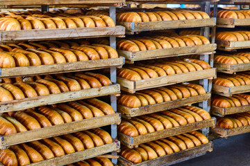 Freshly baked bread rolls resting in wooden trays cooling after oven baking in a bakery