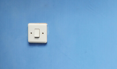A close-up, centered shot of a white light switch mounted on a vibrant blue wall, creating a stark contrast.