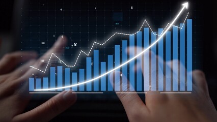 An individual uses a keyboard while analyzing a financial graph displaying upward trends and data, embodying growth, analysis, and digital innovation in business. Copula