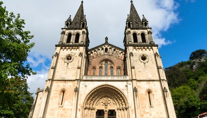 Fototapeta premium Front facade of a historic church, light beige stone, tall spires, arched entryway