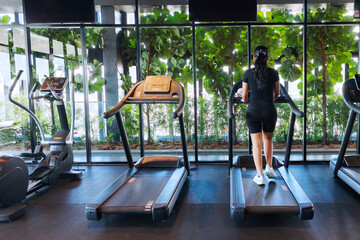 Woman exercising on a treadmill at the gym. A woman is walking on a treadmill at the gym, with her...