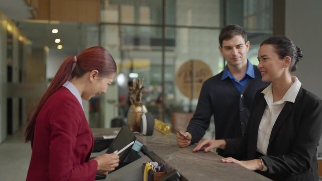 Hotel Receptionist Handing Key Card to Guest at Modern Lobby Front Desk During Check-In Process, Concept of Hospitality, Customer Service