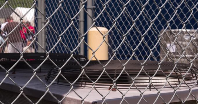 Industrial air conditioner fans spinning behind fence 4k