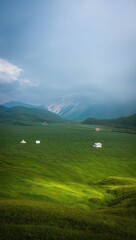 Fototapeta premium Rolling Green Hills With Scattered Houses Under Cloudy Sky