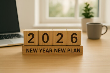 Wooden blocks on a desk showing 2026 New Year New Plan. Concept for goals, resolutions, and business strategy for the upcoming year.