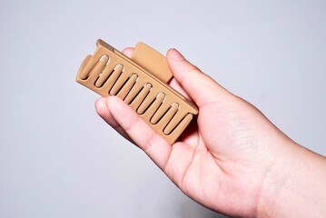 Women hand holding brown hair claw, grip, or clip object isolated on horizontal ratio plain background.