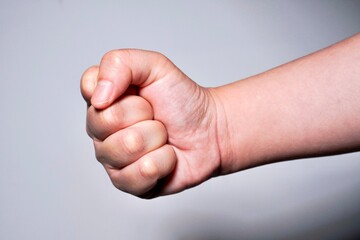 Firm clenched hand gesture pose isolated on horizontal gray background.