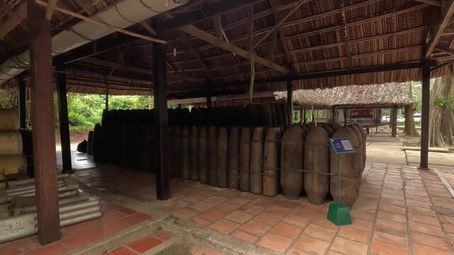 Leftover bomb shells from the Vietnam War neatly arranged under a thatched roof at the Cu Chi Tunnels.