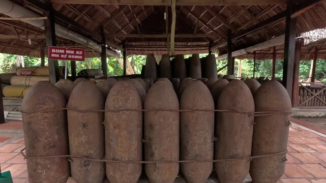 Rusty MK82 bomb shells on display under a thatched roof at the Cu Chi Tunnels in Vietnam, showcasing remnants of the Vietnam War.