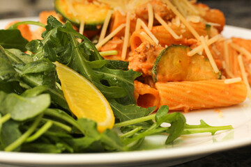 Closeup of prepared rigatoni pasta dish with zucchini and arugula