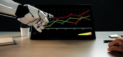 A robotic hand interacts with a touchscreen displaying financial data, showcasing growth trends in...