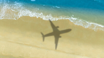 Aerial view of shadow passenger plane silhouette and sandy beach blue sea with waves at sea beach summer vacation sea travel concept	
