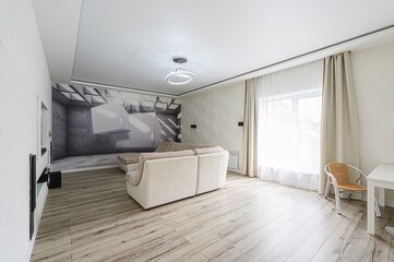 modern living room with light wood floors, a beige sectional sofa, and a feature wall with a geometric design. Large windows let in ample light