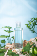 Generated ImA clear cosmetic bottle filled with transparent liquid, placed among natural elements with green leaves and wooden pieces on a blue background.age