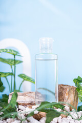Generated IA clear cosmetic bottle filled with transparent liquid, placed among natural elements with green leaves and wooden pieces on a blue background.mage