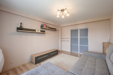 cozy living room featuring a gray sofa, wooden furniture, and soft lighting. Walls painted in light pastel color with decorations and shelves