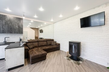 Cozy interior with a brown sectional sofa, modern kitchen, white textured wall, and a sleek black...