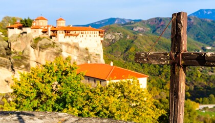 Naklejka premium Rocky mountaintop monastery with autumn foliage and a wooden cross