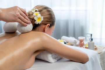Hot herbal ball spa massage body treatment, masseur gently compresses herb bag on woman body....
