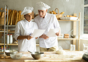 Elderly man and woman checking documents in bakery