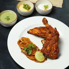 roasted chicken leg quarters with crispy golden brown skin with fresh green thyme leaves on white plate on dark wooden boards, view from above