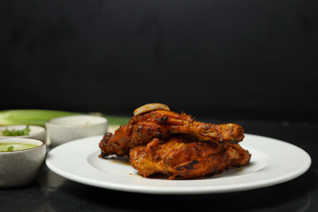 roasted chicken leg quarters with crispy golden brown skin with fresh green thyme leaves on white plate on dark wooden boards, view from above