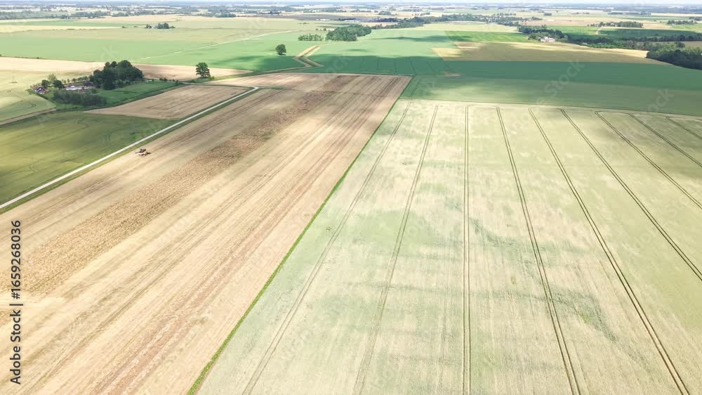 Poster aerial pan of green and golden crop fields with visible tractor path lines and machinery