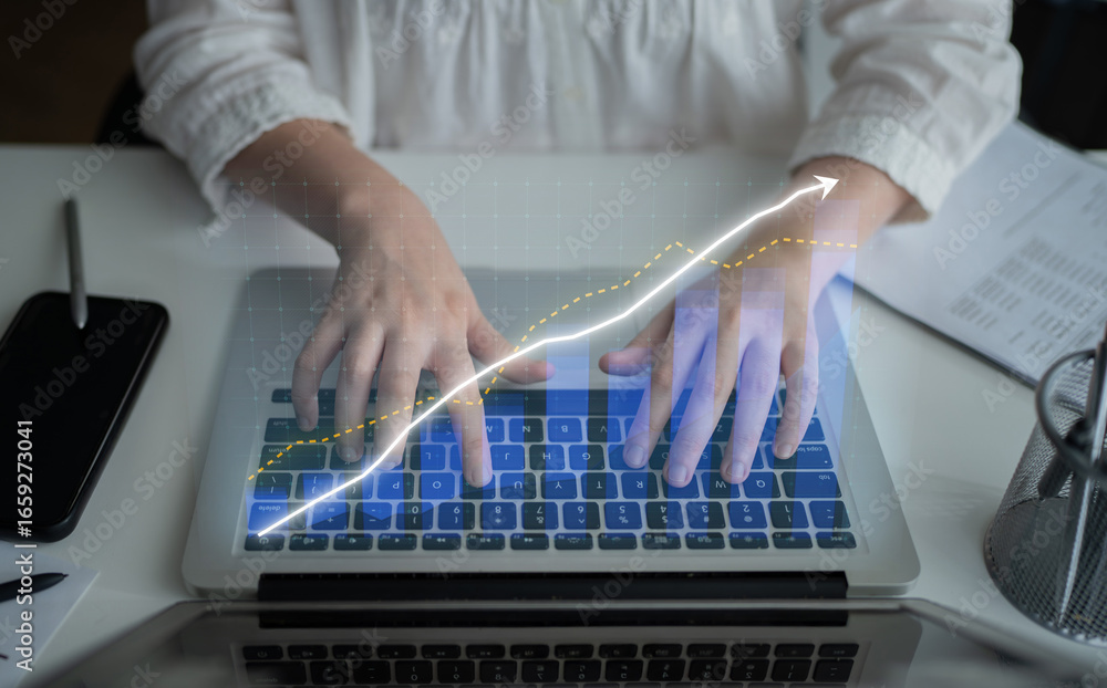 Poster a close-up view of hands typing on a laptop, featuring a digital graph overlay that symbolizes growt