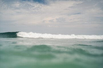 Ocean wave cresting under cloudy sky