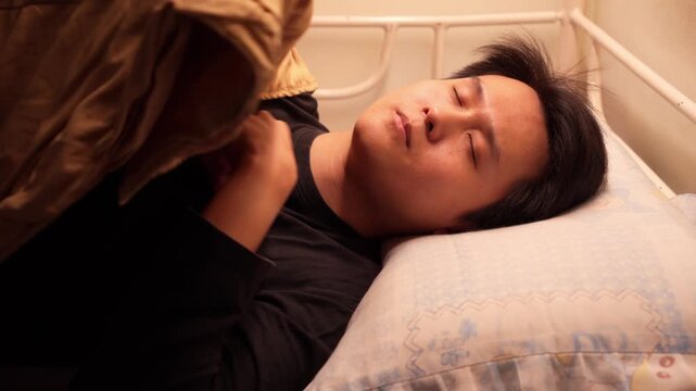 Chinese man going to sleep in a little bed. Close up