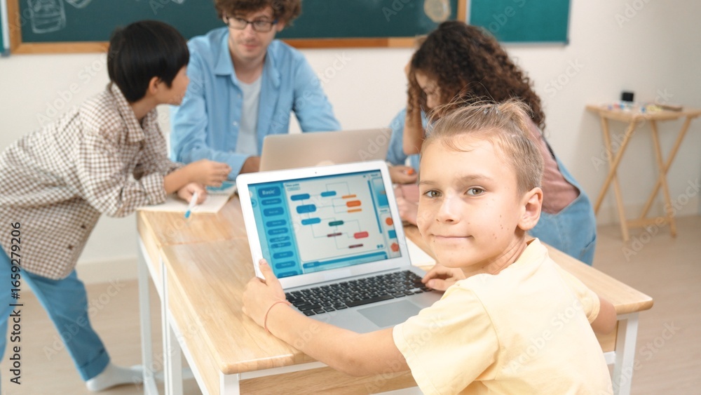 Poster cute caucasian boy coding program and looking at camera in stem technology class while group of dive