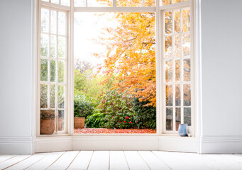 Obraz premium Bright autumn view through open windows showcasing vibrant foliage and tranquil garden in a cozy interior