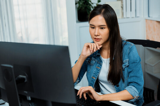 Working young beautiful asian creative manager focusing on pc, creating with new website design on new social media online channel planning with blue jeans shirt at modern home office. Stratagem. - Powered by Adobe