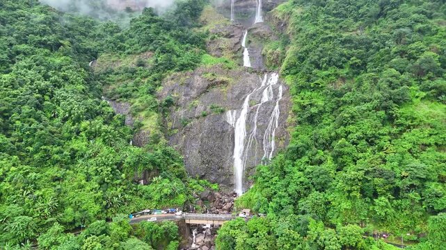 Aerial shot of beautiful waterfall from above the mountains surrounded by trees