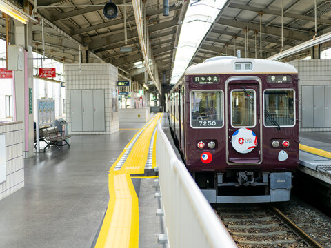 2025年7月川西能勢口駅に停車する能勢電鉄の大阪関西万博ラッピング列車7000系を最後尾から撮影
