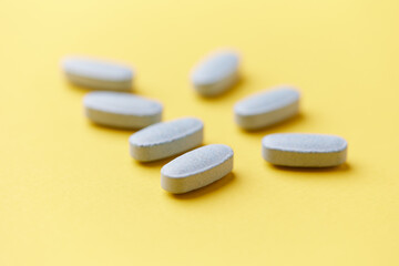 Multivitamin tablets on bright paper background. Close up. Copy space	