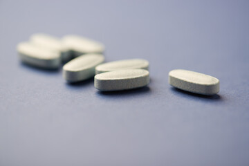 Multivitamin tablets on dark paper background. Soft focus. Close up. Copy space	
